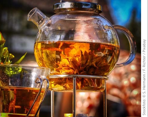 Eine Teekanne aus Glas steht auf einem Stövchen